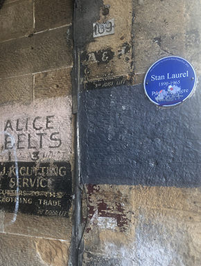 Wall with old signs including a Stan Laurel recognition sign obscured by vandals