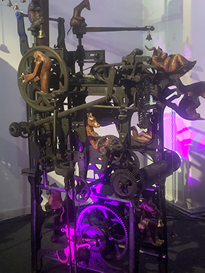 Sculpture with wheels and bells, purple light