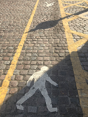 Waling man paining on cobblestones in pedestrian lane