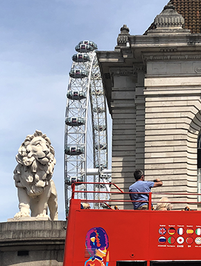 Tour bus passing lion sculpture and ferris wheel