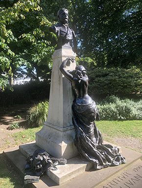 Bronze of dramatic woman against pillar holding bust of Gilbert Sullivan