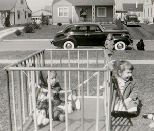 two little girls outside, the baby in a playpen